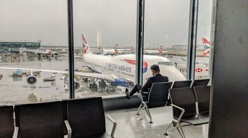 Man in gray shirt sitting on black chair at the London airport