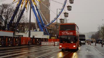 Open-top tour bus on the road and a ferris wheel on the left