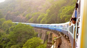 Person enjoying scenic train ride through green hills