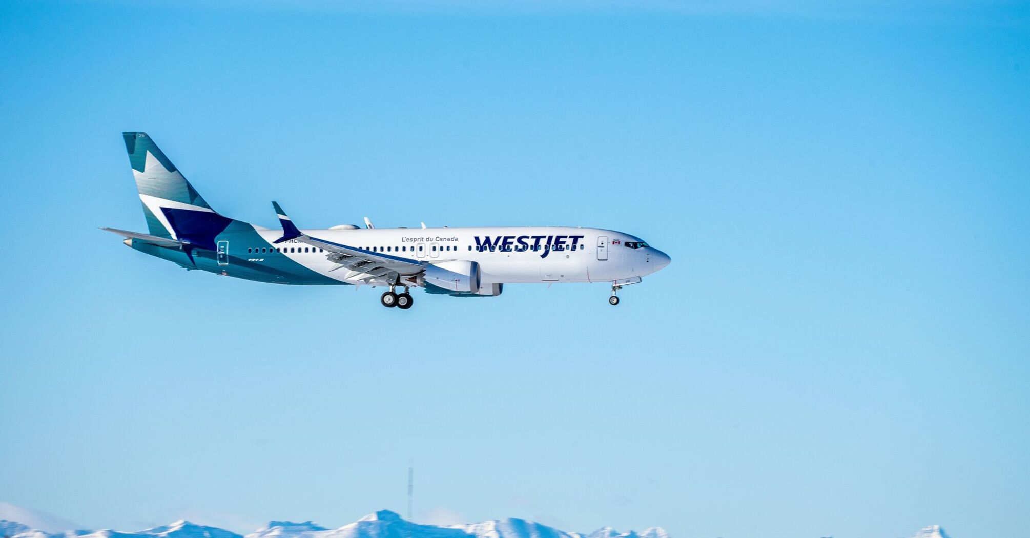 White and blue WestJet airplane flying during daytime
