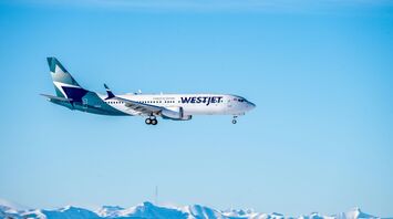 White and blue WestJet airplane flying during daytime