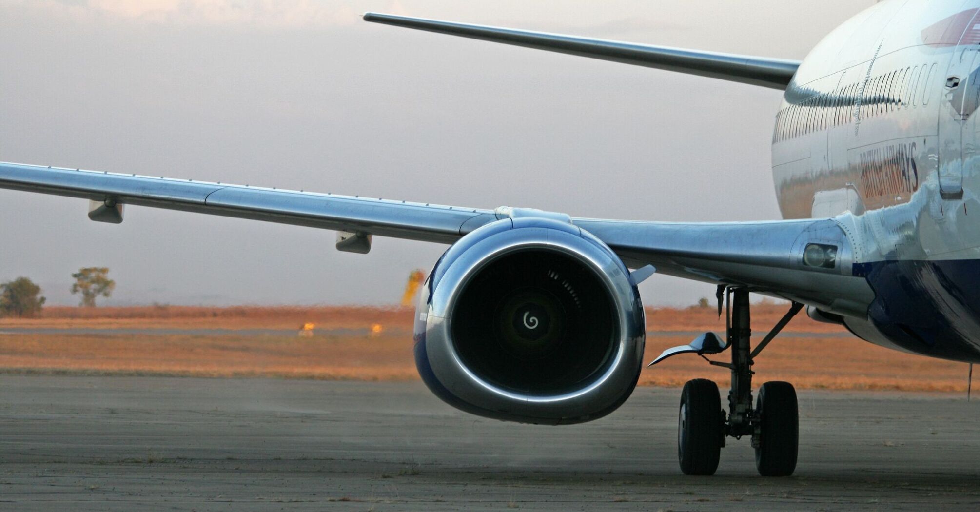 Close-up of an airplane engine and landing gear on the runway