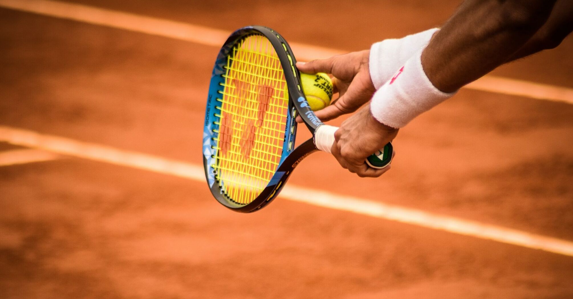 Tennis player holding racket and ball on clay court