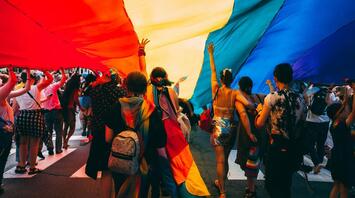 People running forward under a rainbow flag