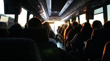 Passengers seated in a motorcoach, sunlight streaming through the front window