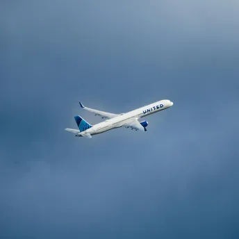 A large passenger jet flying through a cloudy blue sky