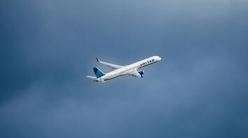 A large passenger jet flying through a cloudy blue sky