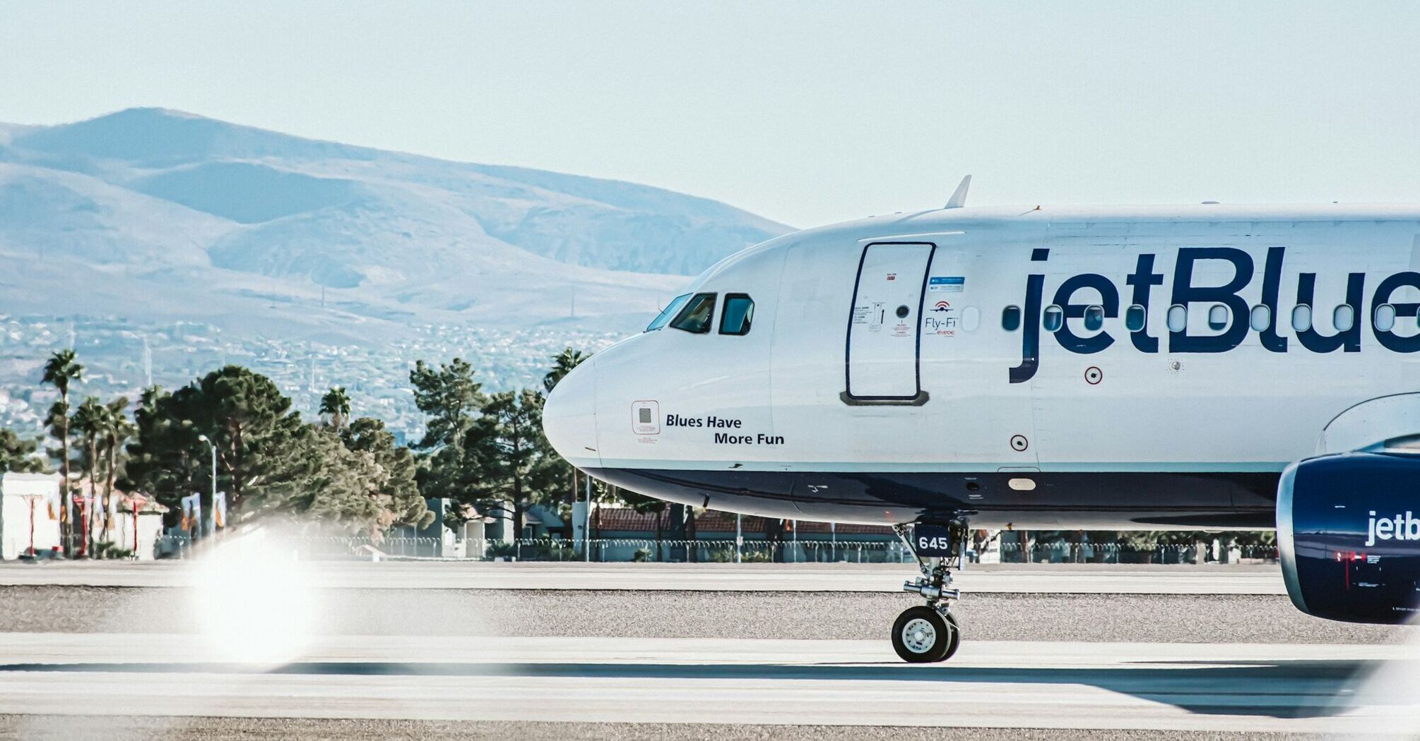 JetBlue aircraft on the runway with mountain backdrop during a clear day