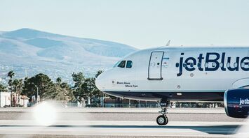 JetBlue aircraft on the runway with mountain backdrop during a clear day