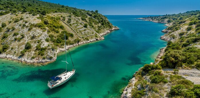 Aerial photography of white boat near body of water between green mountain during daytime