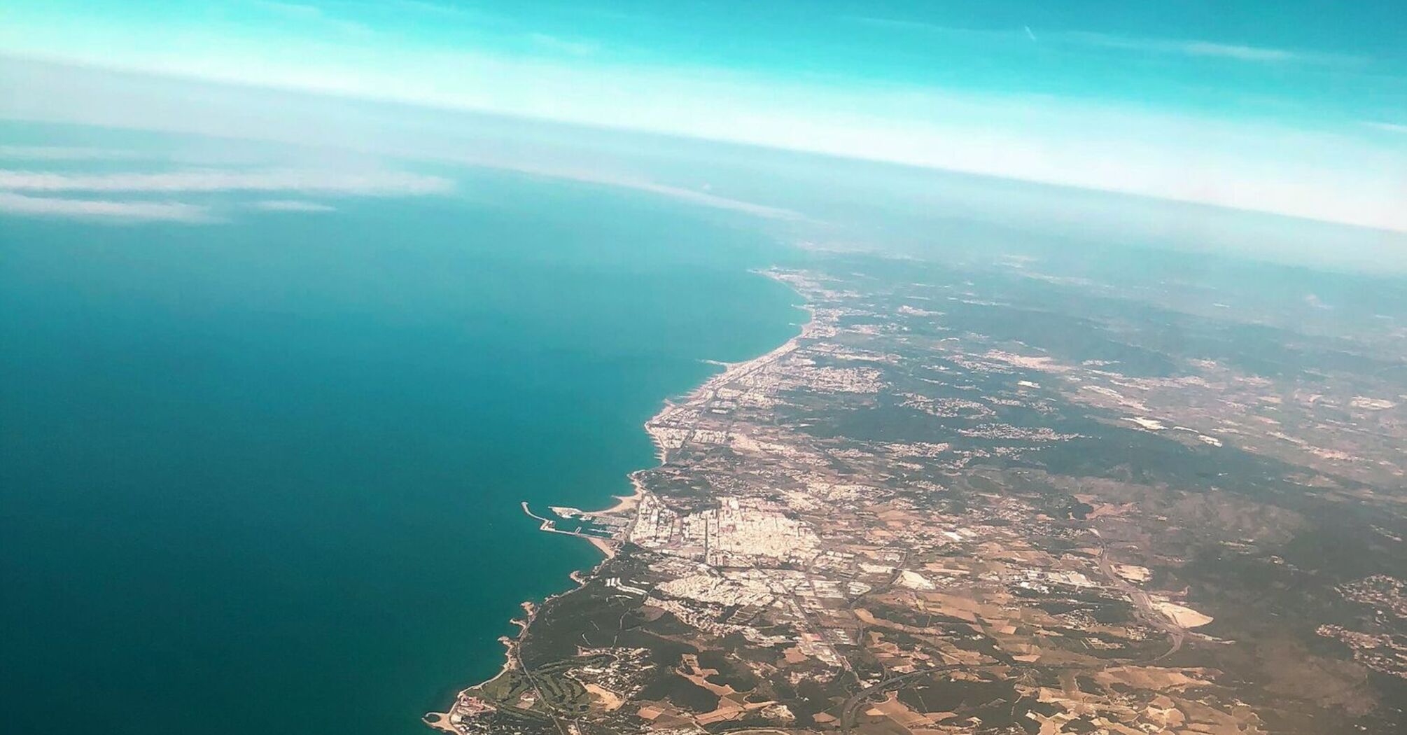 Aerial view of the coastline of Barcelona, Spain, showcasing the cityscape adjacent to the clear blue waters of the Mediterranean Sea