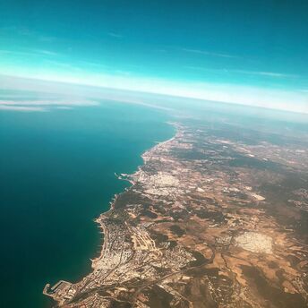 Aerial view of the coastline of Barcelona, Spain, showcasing the cityscape adjacent to the clear blue waters of the Mediterranean Sea