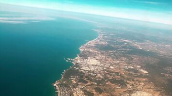 Aerial view of the coastline of Barcelona, Spain, showcasing the cityscape adjacent to the clear blue waters of the Mediterranean Sea