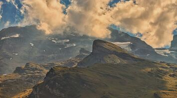 A view of a mountain range with clouds in the sky