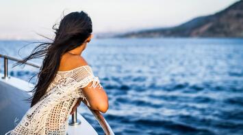 Girl stands on board a ship and admires the ocean