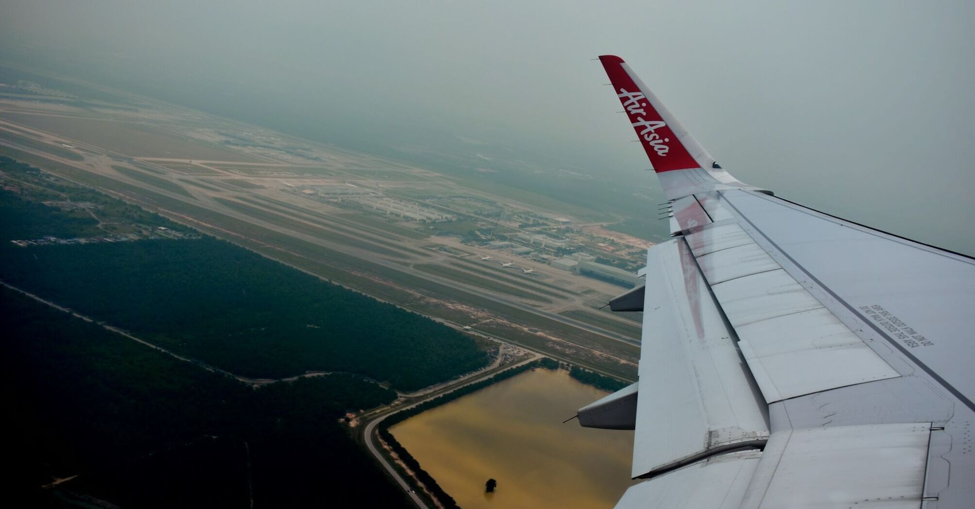 AirAsia plane flying over an airport runway