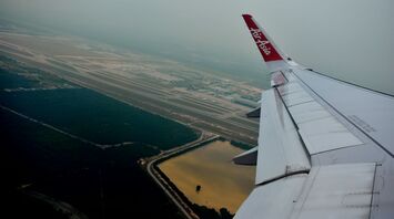 AirAsia plane flying over an airport runway