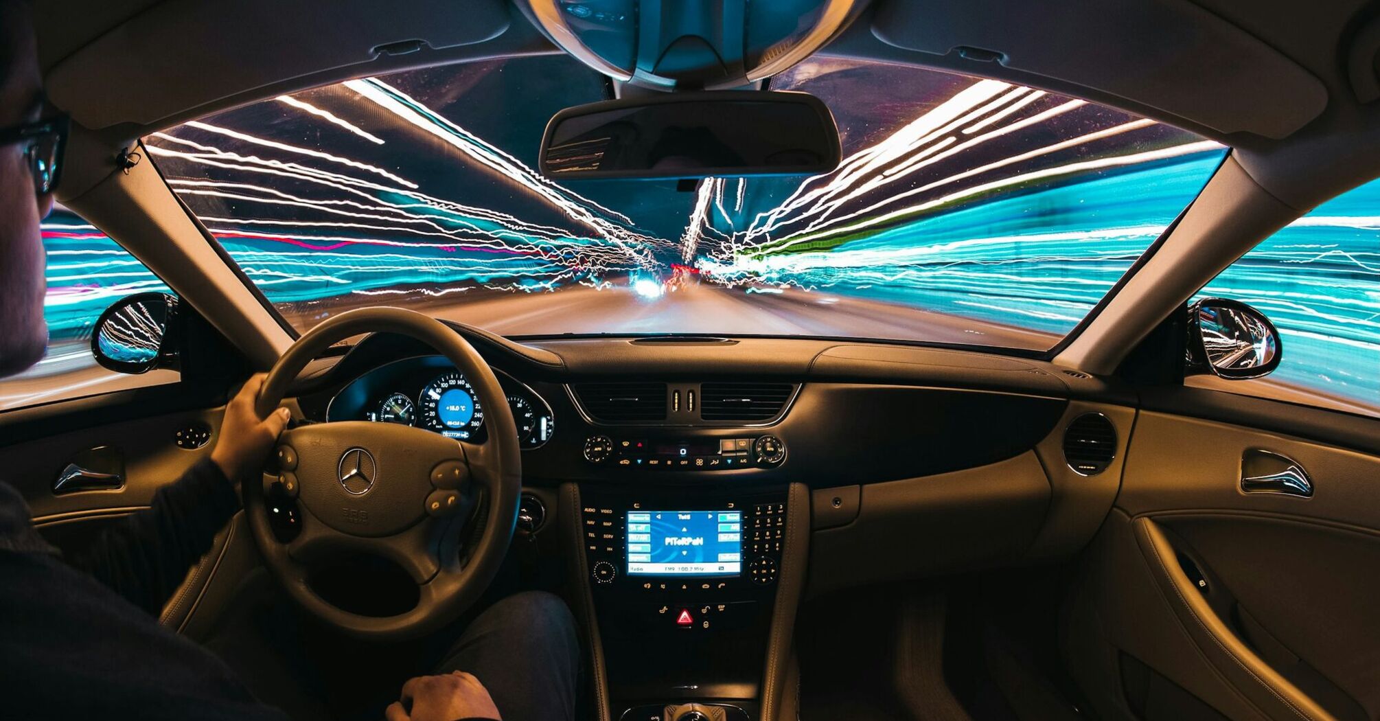 A driver at the wheel of a car with streaks of light representing speed and technology