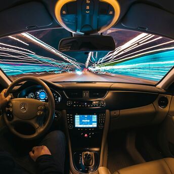 A driver at the wheel of a car with streaks of light representing speed and technology