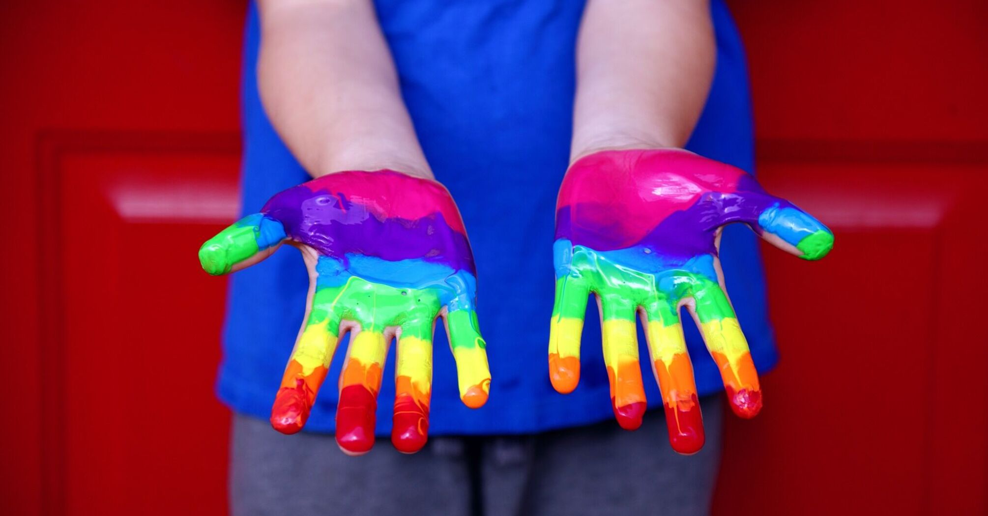 Person hands painted with rainbow colors