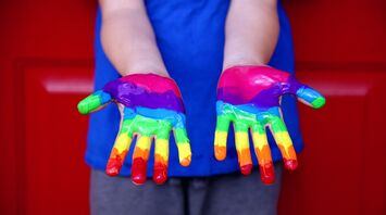 Person hands painted with rainbow colors