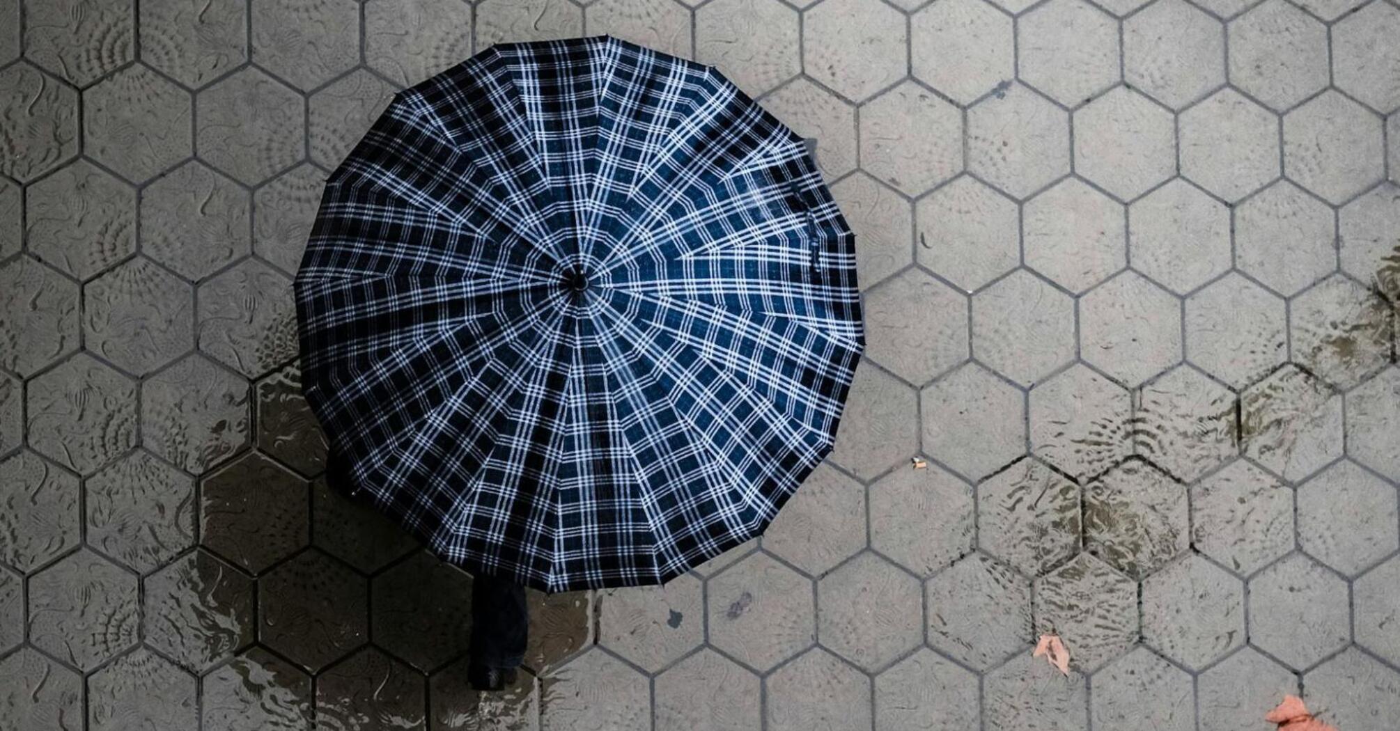 A birds eye view of a person under umbrella and a flooding rain 