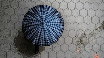 A birds eye view of a person under umbrella and a flooding rain