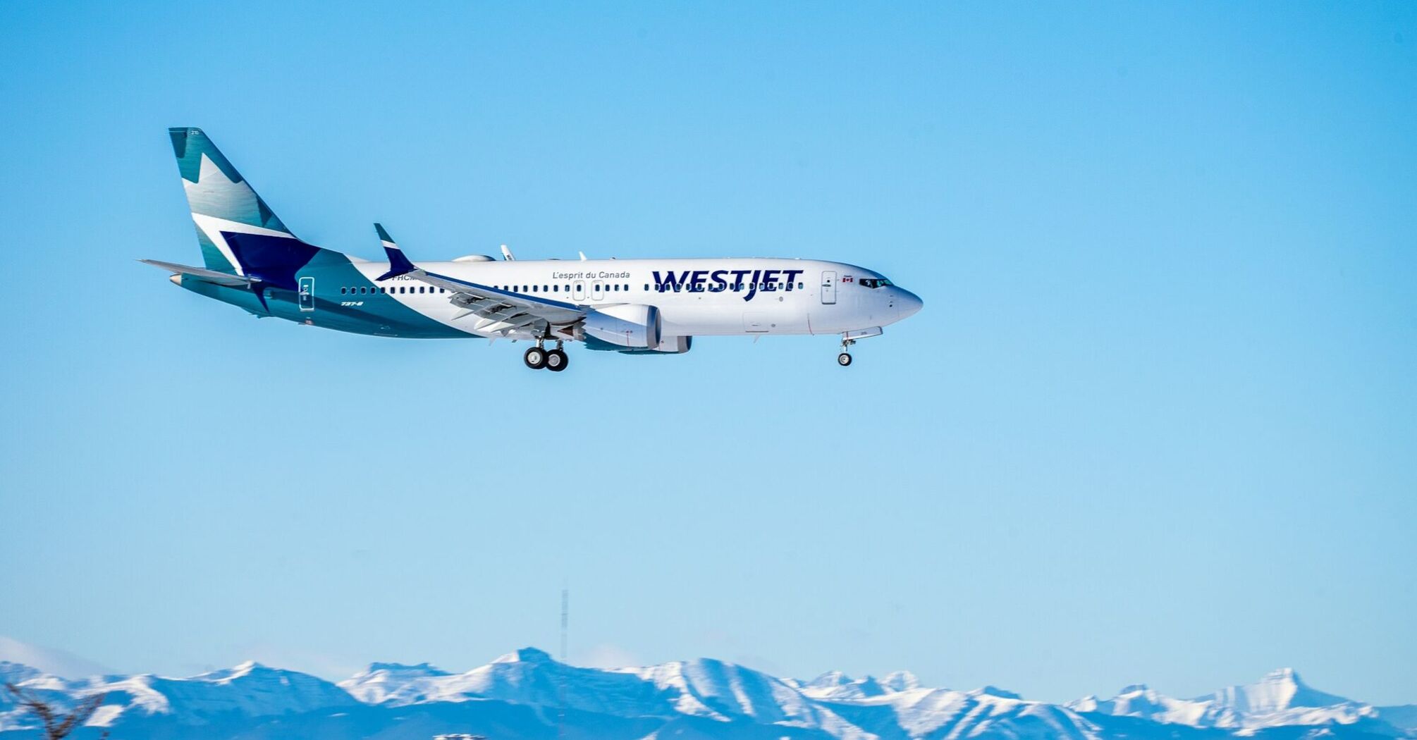 WestJet airplane flying with mountain background