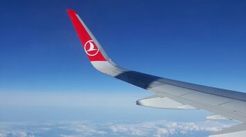 Turkish Airlines airplane wing flying over snow-capped mountains