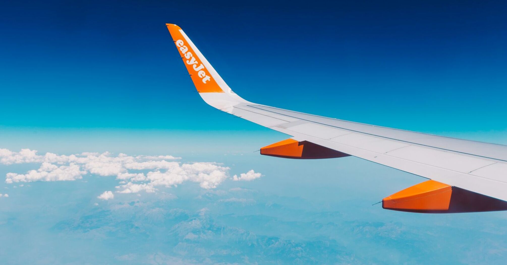 EasyJet airplane wing against blue sky and clouds
