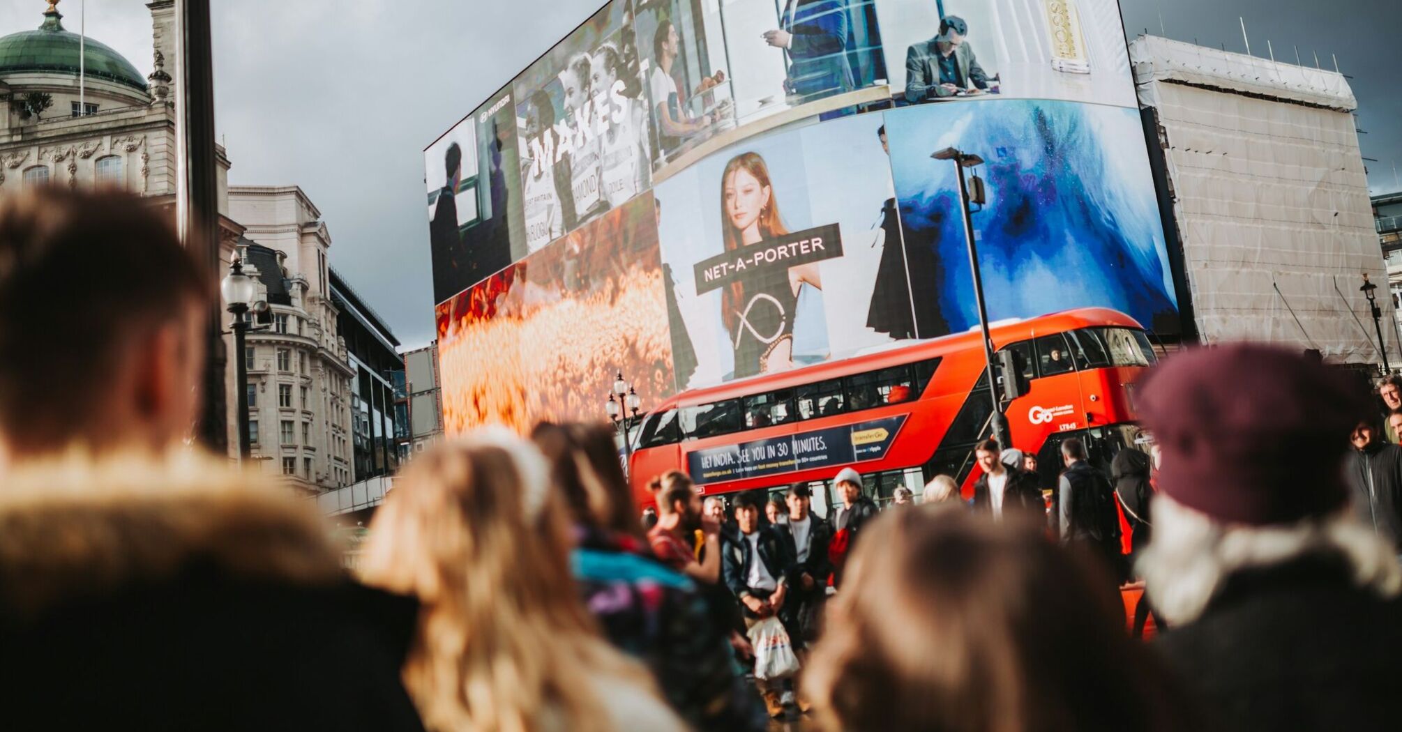 Crowded street in London with double-decker bus and digital billboards