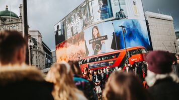 Crowded street in London with double-decker bus and digital billboards