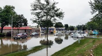Flooded street with submerged cars and buildings in the background