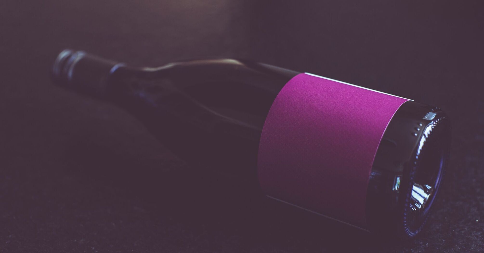 A bottle of wine with a purple label lying on its side