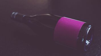 A bottle of wine with a purple label lying on its side