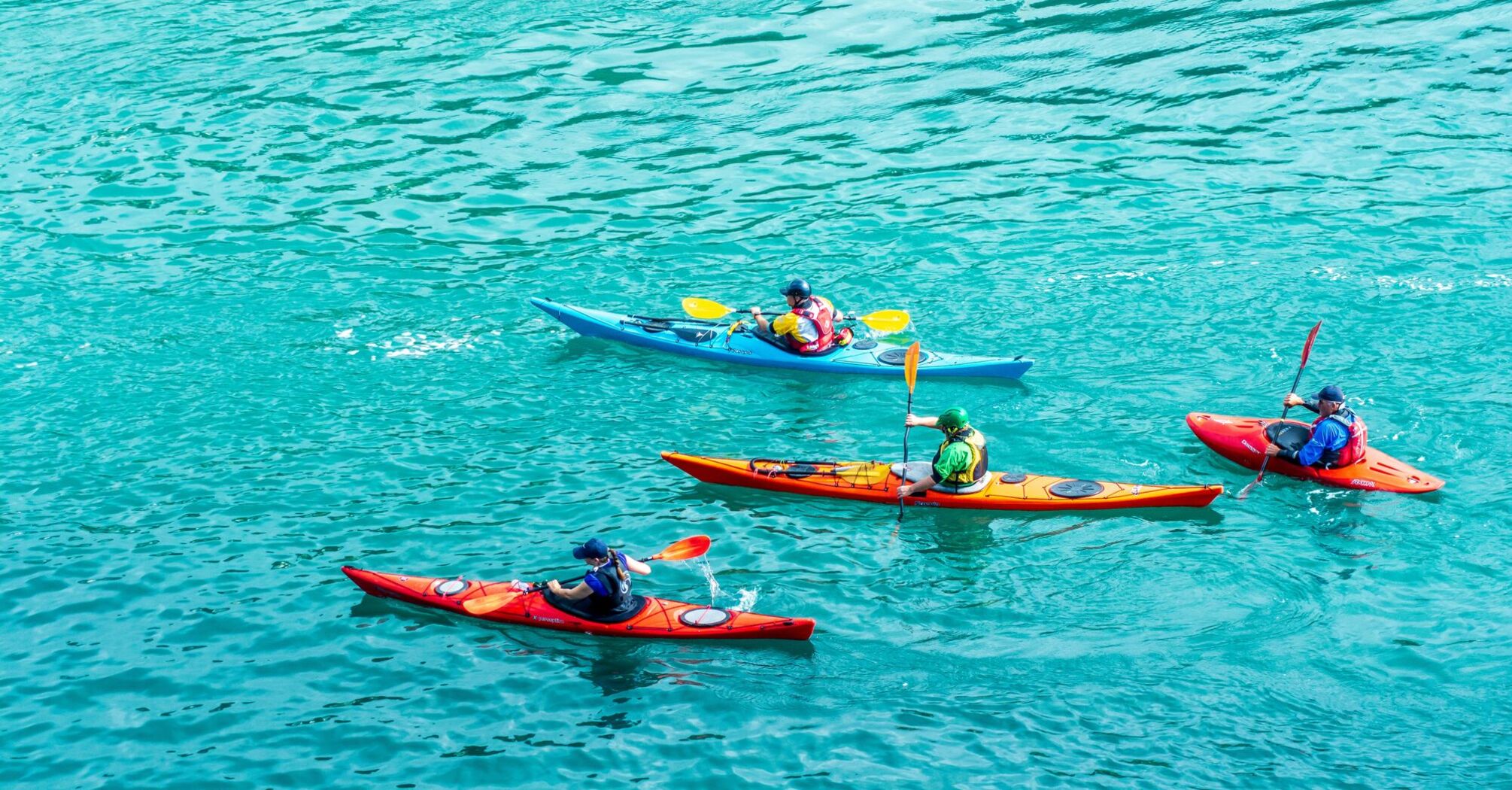several persons riding kayaks on body of water during daytime
