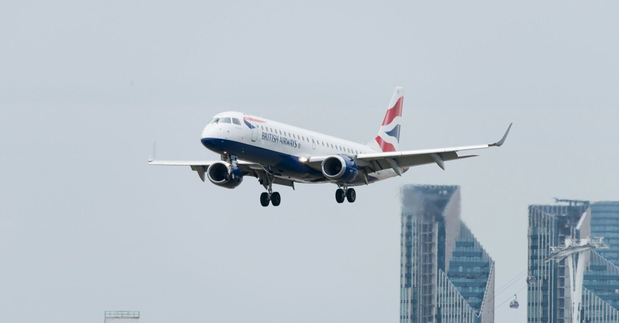 British Airways plane landing with city skyline in the background