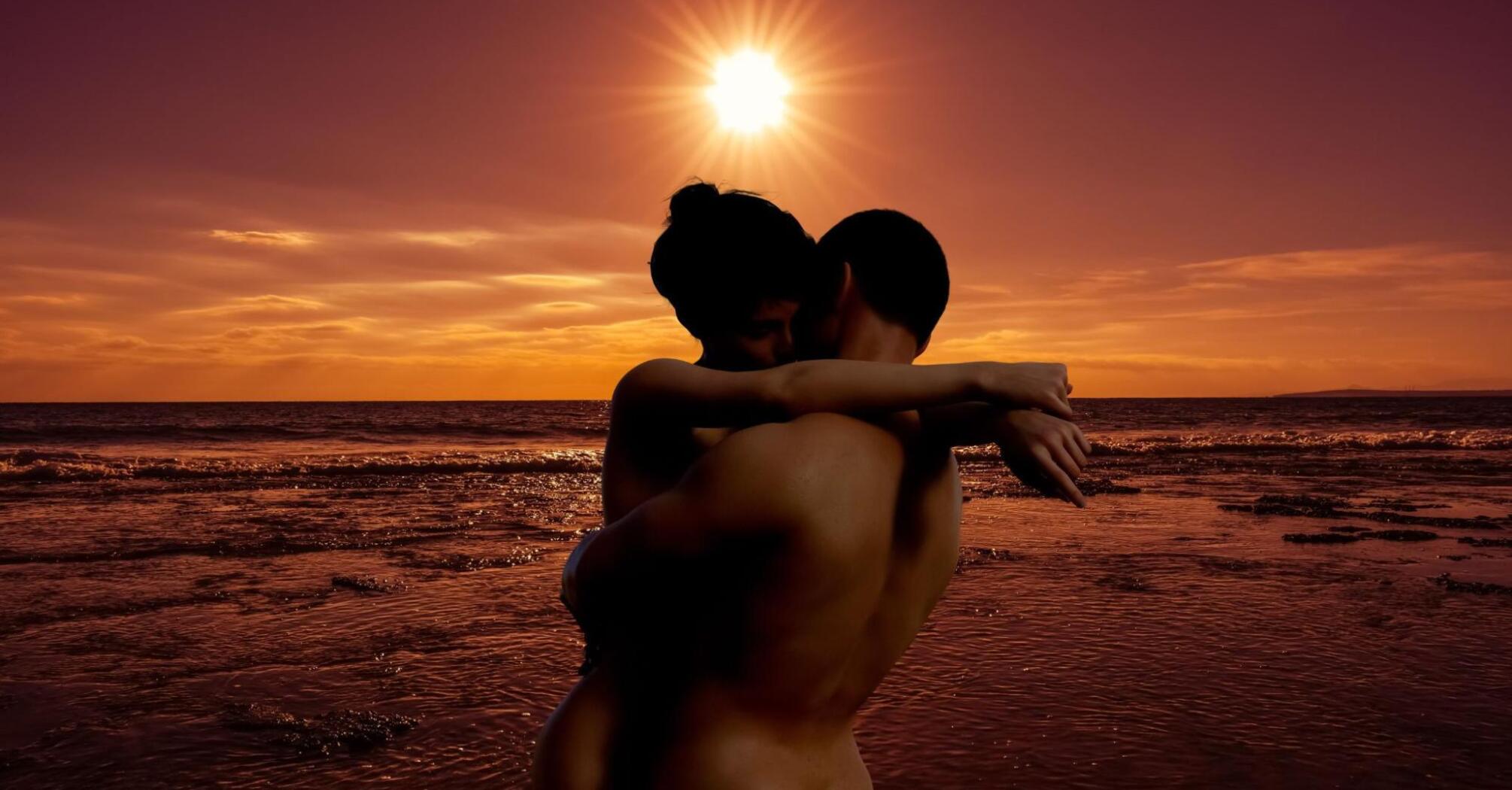 Naked couple on the beach in sunset