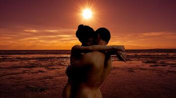 Naked couple on the beach in sunset