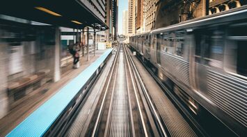 High-speed train passing through a cityscape with tall buildings