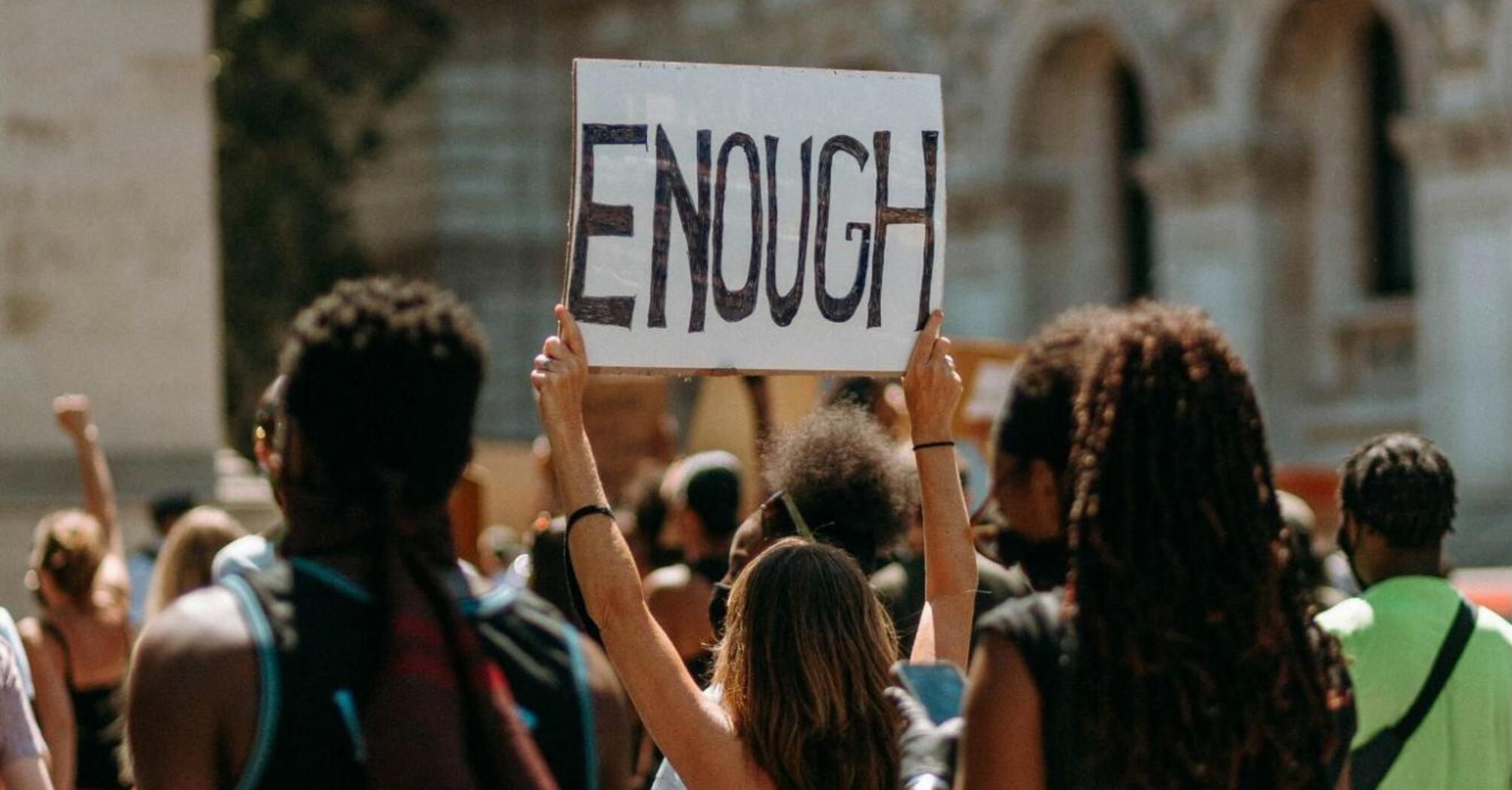 Protesters holding a sign that says 'ENOUGH'