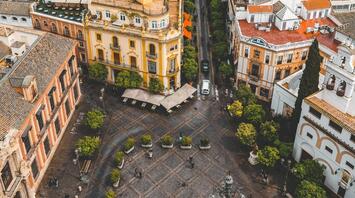Aerial view of a historic square in a Spanish city with traditional architecture and a fountain