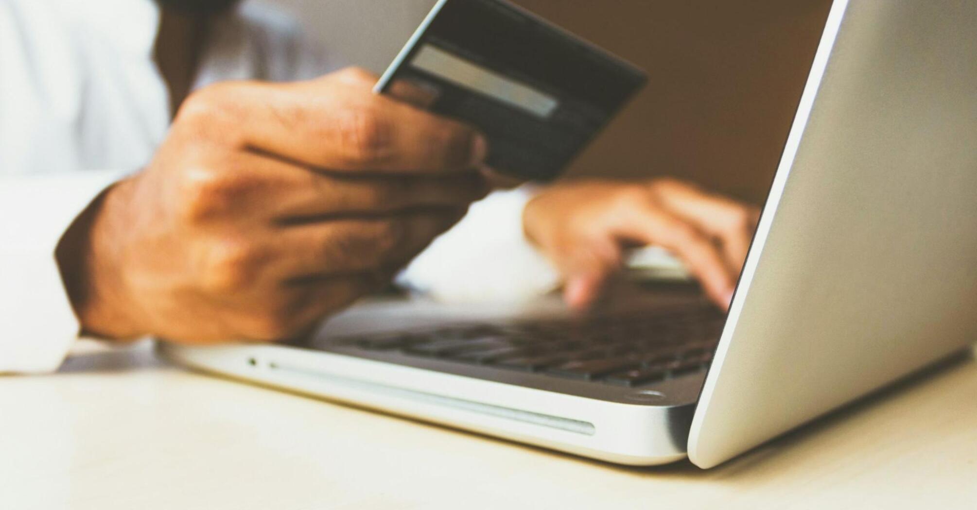 A person using a credit card while typing on a laptop