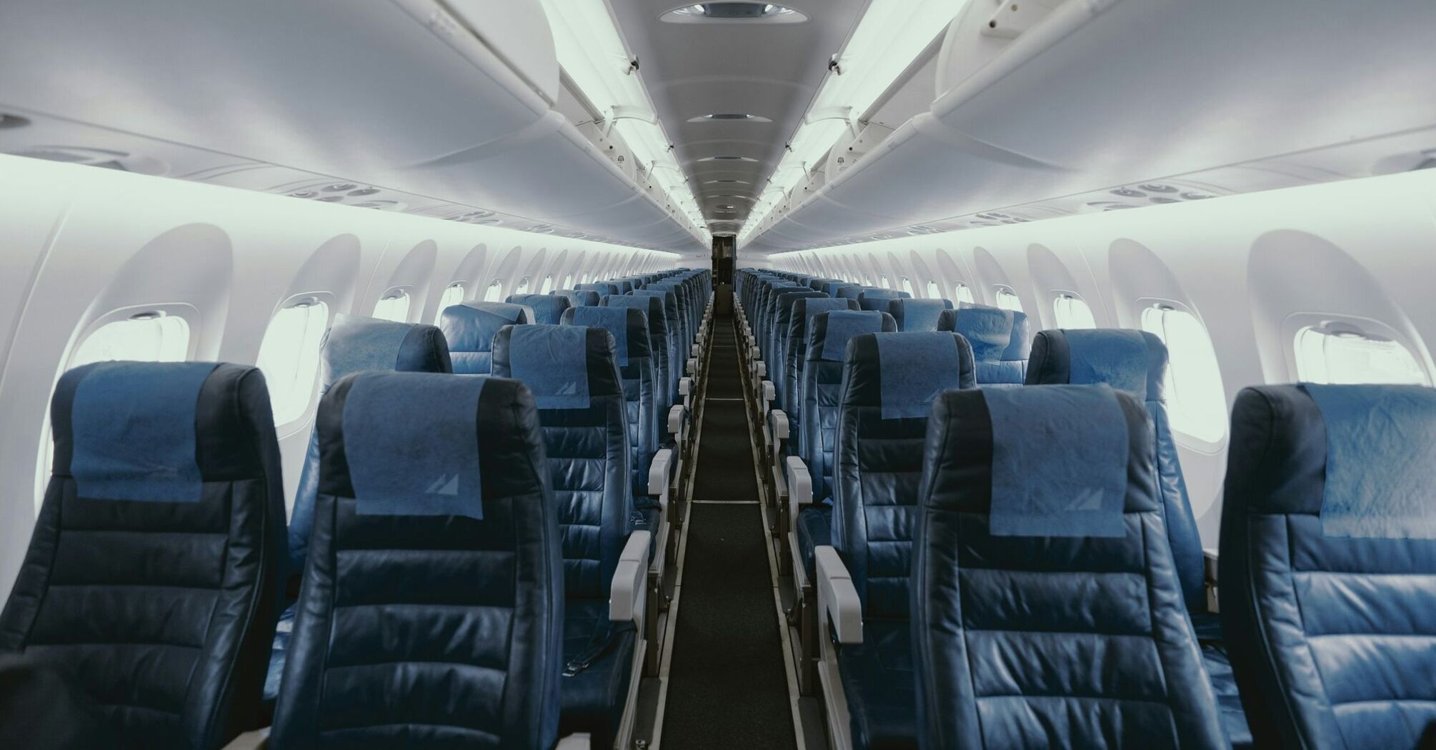 Empty airplane cabin with rows of blue seats