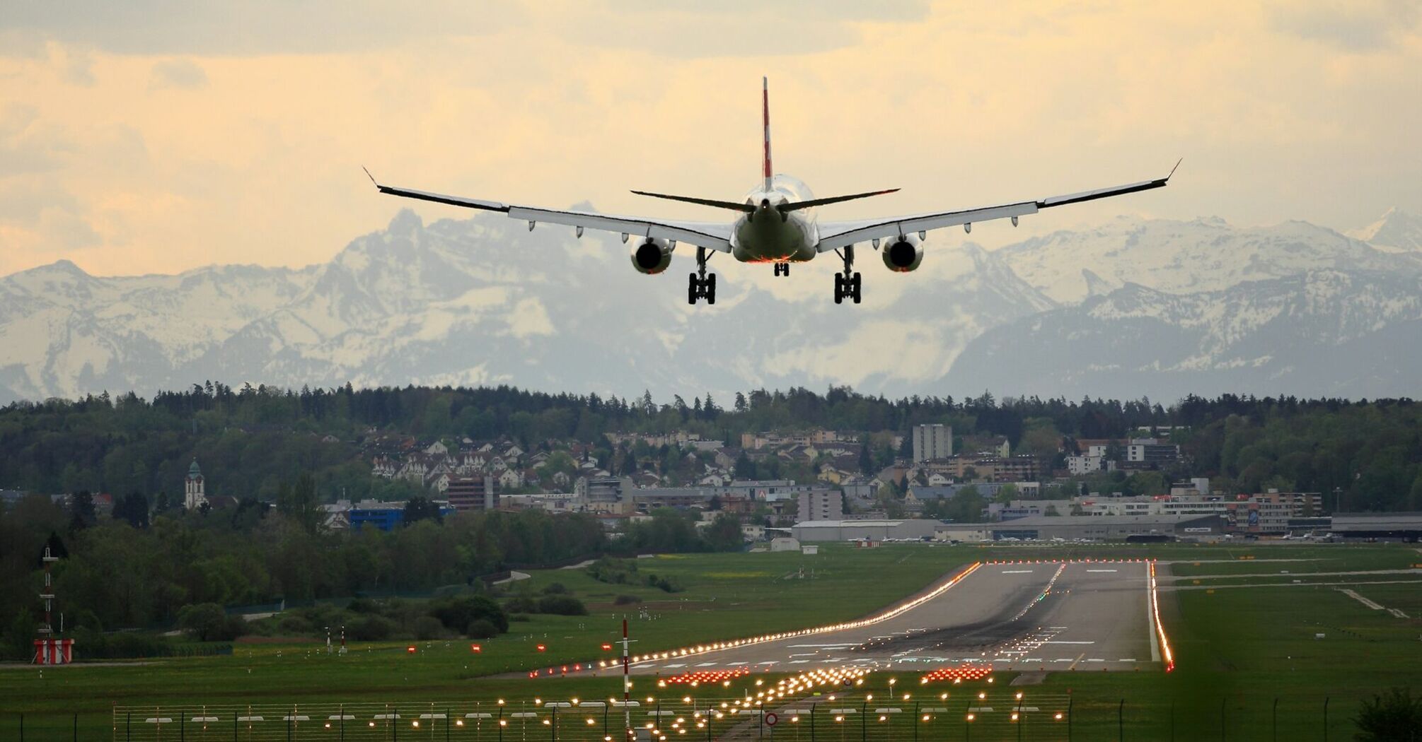 An airplane landing on a runway with mountains in the background
