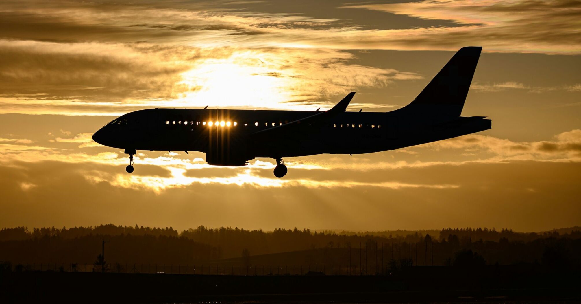 Airplane silhouetted against a sunset sky during landing