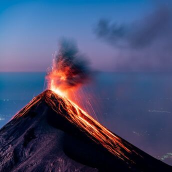 Eruption of a volcano with glowing lava and ash plume at dusk