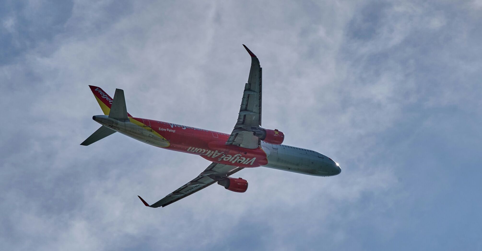 red and white vietjetair airplane flying in the sky