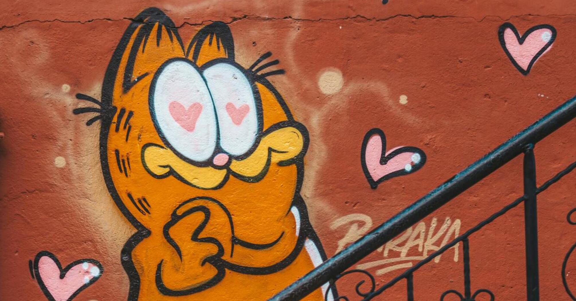 Graffiti of Garfield with heart eyes on a colorful wall near a staircase