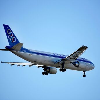 a blue and white Olympic Airways jet airliner flying in the sky